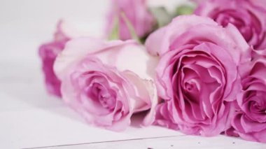 Pembe güller ve pembe arka planda gül yaprakları.