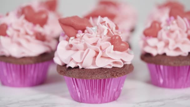 赤いベルベットのカップケーキピンクイタリアのバタークリームの霜降りとハートとキス形の赤いチョコレートで飾られています — ストック動画