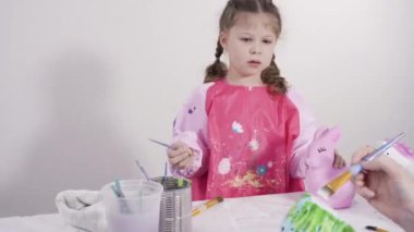 Zaman aşımı. Küçük kız evde eğitim projesi için akrilik boyayla heykelcikler boyuyor..