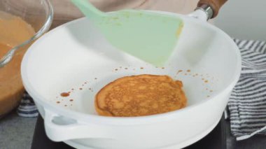 Time lapse. Step by step. Frying pumpkin pancakes batter on a white frying pan.