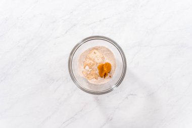 Flat lay. Mixing ingredients in a glass mixing bowl to prepare pumpkin mug cake.