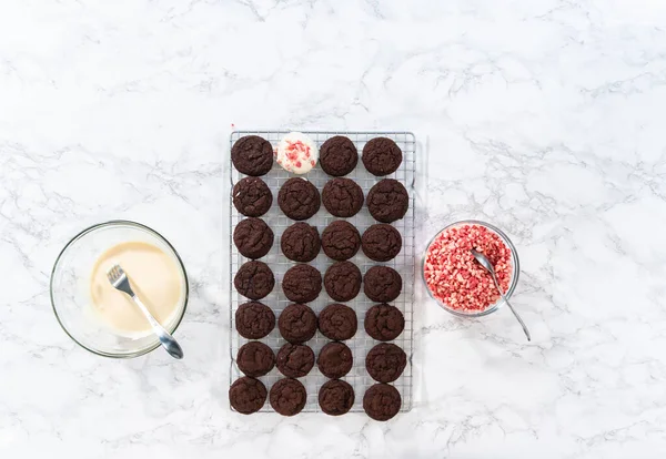 Flat lay. Dipping chocolate cookies into the melted white chocolate to prepare peppermint white chocolate cookies.