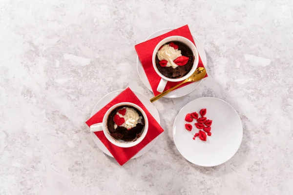 Flat lay. Chocolate mug cakes garnished with whipped cream and chocolate hearts and lips.