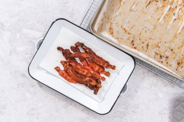 Düz yatıyordu. Beyaz tepside pişmiş pastırma şeritleri ve kağıt havlu..