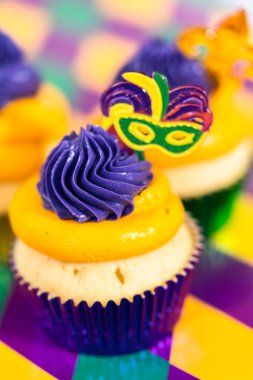 Mardi Gras vanilyalı kekler folyo kaplarda ve İtalyan tereyağlı kremayla süslenmiş..