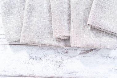 Ahşap beyaz bir masada doğal renkte keten bir peçetenin yakın görüntüsü..