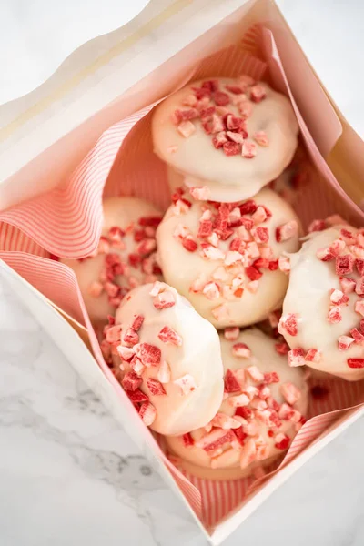 Packing freshly baked peppermint white chocolate cookies into a white paper box.