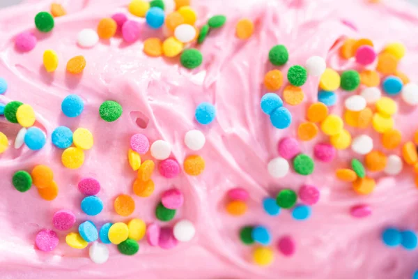 가까이 분홍빛 바닐라 버터크림을 무지개 스프링 클링으로 케이크 — 스톡 사진