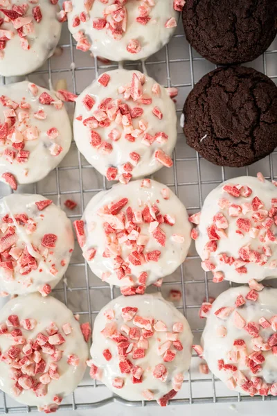 Dipping chocolate cookies into the melted white chocolate to prepare peppermint white chocolate cookies.