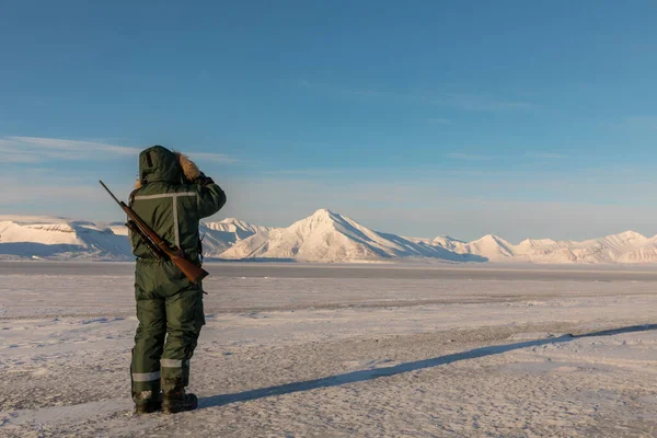 Egy férfi puskával és távcsővel az északi sarkvidéken Svalbardon. — Stock Fotó