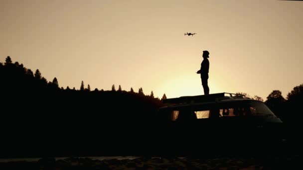 Silhueta Homem levanta um drone no ar na natureza ao pôr do sol — Vídeo de Stock