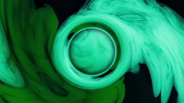 Cercle abstrait gouttes d'encre verte d'en haut mélangeant dans l'eau, tourbillonnant doucement sous l'eau sur fond noir — Video