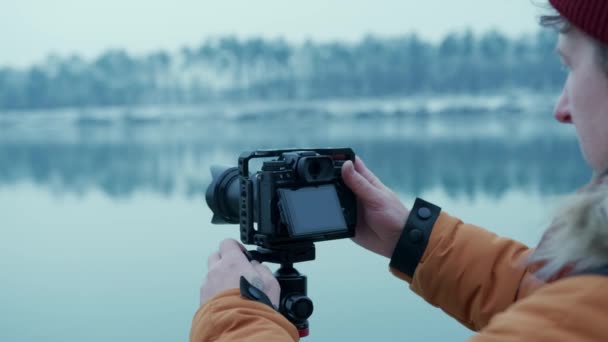 Hiker taking pictures of snowy nature in winter Lake background winter forest. — Wideo stockowe