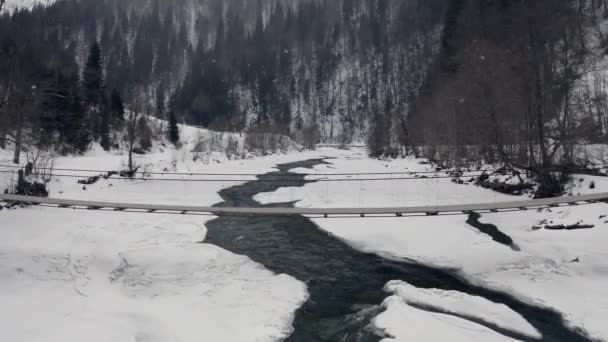 겨울 숲에서 산을 넘는 오래 된 목조 다리. 공중에서의 광경 — 비디오