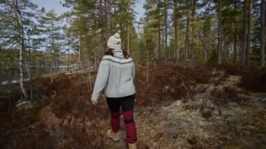 Kız baharda ormanda yürür. Norveç ulusal parkında bir kadın yürüyor. Yavaş parola