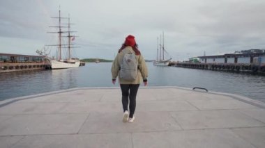Genç bir kadın set boyunca yürür. Oslo Norveç 'te gemi iskelesi