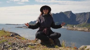 Gezgin kadın, Lotus pozisyonunda huzur içinde meditasyon yapıyor. Sağlıklı sağlık yaşam tarzı Norveç manzarası lofotensi