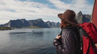 Sırt çantalı bir gezgin kız Lofoten 'in güzel manzarasına bakıyor..
