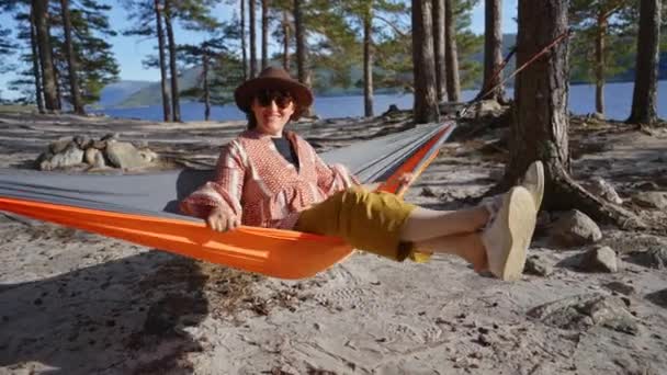 女旅行者坐在游客的吊床上 在阳光灿烂的松林里荡秋千 享受着她的孤独 和平与宁静 自然界中的自然时刻和个人活动 — 图库视频影像