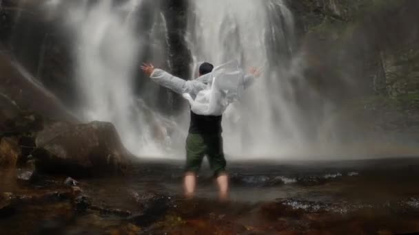 Šťastný Muž Průhledném Plášti Stojí Rukama Úpatí Vodopádu Norway Skály — Stock video