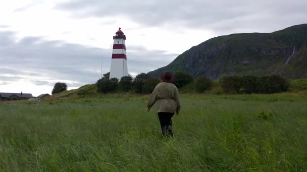 灯台の近くを歩いて美しい自然景観を楽しむ女性 孤独な娘だ 北に素晴らしい景色の屋外ビュー 旅と冒険 ノルウェーを探索 — ストック動画