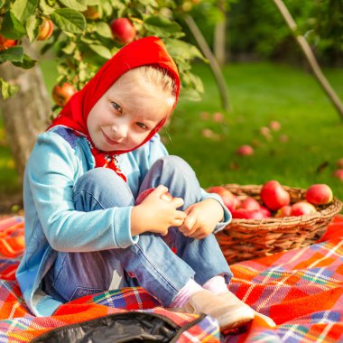 Güzel küçük kız elma ağacının altında oturuyor..