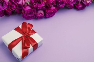 Gift box and flowers on color background with space for text