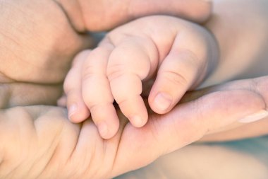 Mother holds newborn baby hand. Care concept. Toned photo