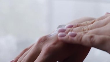 Elindeki kuru cilde krem süren bir kadın. Cilt bakımı kavramı