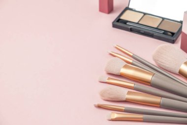 Makyaj fırçaları hazır ve pembe arka planda gölgeler var. Makyaj konsepti. Boşluğu kopyala