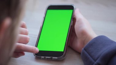 iPhone 13 Pro akıllı telefon kullanan bir kız yeşil ekran izliyor. Yeşil ekran 12.02.22 Minsk, Belarus 'taki telefondan taklit ediliyor.