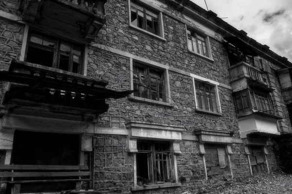 Black and white photo of old abandoned partially collapsed building with intricate stonework, ruined balconies, crashed windows. Desolation and destruction — Stock Photo, Image