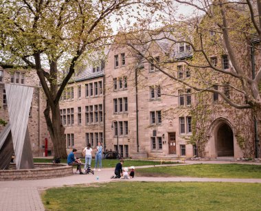 Toronto, Kanada - 05: 15: 2021: Toronto şehir merkezindeki Toronto Üniversitesi 'nin arazisindeki Teefy Hall binasının önündeki parkta eğlenen Torontonlular