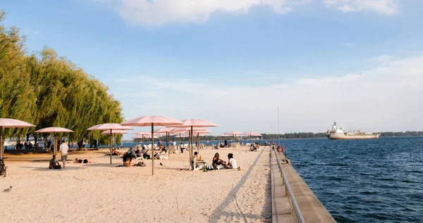 Toronto, Kanada - 08 29 2021: Toronto şehir merkezindeki Torontonlular Ontario Gölü 'nün en iyi mavi suları olan Sugar Beach' in pembe umbllrelas altında dinleniyorlar..