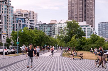 TORONTO, CANADA - 07 12 2021: Humber Bay Shores Parkı 'nda dinlenen insanlar, Etobikola ilçesinin tarihi ve manzaralı bir parçası olan Humber Bay Sahilleri' nin modern apartmanlarının önünde,
