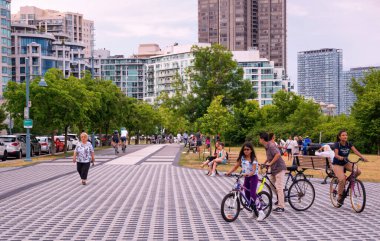 TORONTO, CANADA - 07 12 2021: Humber Bay Shores Parkı 'nda dinlenen insanlar, Etobikola ilçesinin tarihi ve manzaralı bir parçası olan Humber Bay Sahilleri' nin modern apartmanlarının önünde,