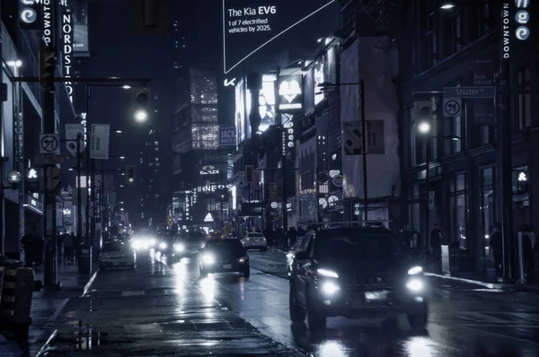 Toronto, Canada - 10 30 2021: Rainy night view along Yonge street in downtown Toronto with bright colorful street sighs, traffic lights, cars headlamps light reflecting in wet asphalt surface — Stock Photo, Image