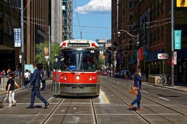 Toronto, Canada - 06 27 2016: City dwellers crossing the street in front of an old streetcar on King at Yonge st. intersection.