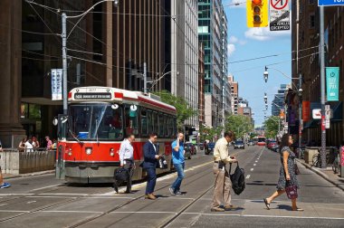 Toronto, Canada - 06 27 2016: City dwellers crossing the street in front of an old streetcar on King at Yonge st. intersection.