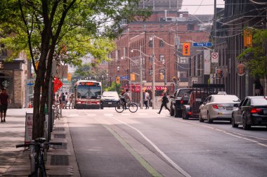 Toronto, Canada - 08 03 2018: Summer view along Sherbourne Street with traffic on junction with King Street in Old Toronto district with a cyclist, cars, people boarding to a bus.