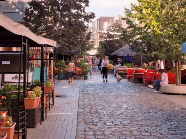 Tbilisi, Georgia - 07 23 2022: Warm summer sunset view along Davit Agmashenebeli avenue with tourists walking beside street cafes canopys.
