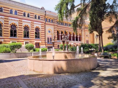 Tbilisi, Georgia - 07 23 2022: Opera and Ballet Theater of Tbilisi building on Shota Rustaveli Avenue with Three Ballerinas fountain seen in hot summer afternoon.