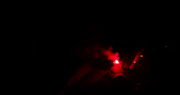 Man waving a flare on the beach at night, holds his hand with fire — Vídeos de Stock