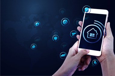Evde elinde akıllı telefon tutan bir kadın ya da erkek. Modern yaşam internetindeki ikonlarıyla, akıllı ev teknolojisiyle. Otomasyon konsepti. Oturma odasında geleceğin yeni yeniliği..