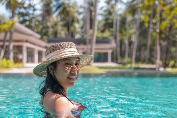 赤い水着を着た幸せなアジアの女性と タイのパンガー島のコ マークのプールでカメラを見てスイミングプールでリラックスしたわらの帽子 リラックスして旅行のコンセプト コンフォートリゾート夏休み — ストック写真