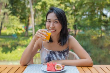 Kadının kamera önünde portakal suyu ve karpuz içen çarkıfelek meyvesine bakışı. Kız öğle yemeğinde meyve yiyor, diyet konseptini seviyor. Sağlık kavramı.