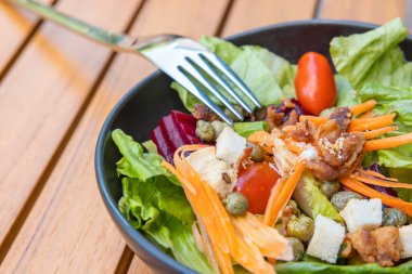 Sotelenmiş sebzeli kahvaltı salatası ve ahşap bir masanın üzerine çatal..