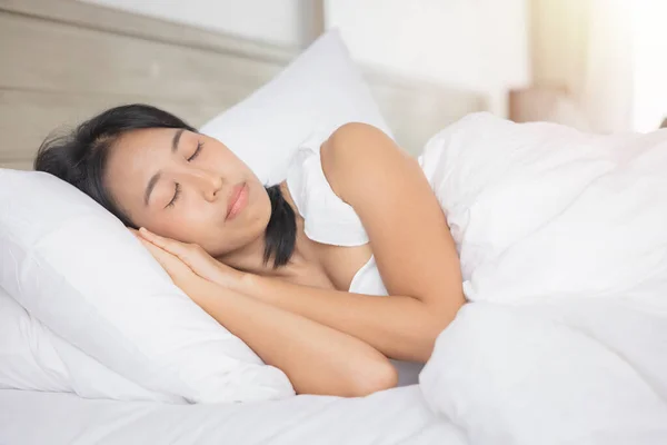 Young asian woman sleeping in bed at bedroom. she is lying on side and relax with eyes closed.