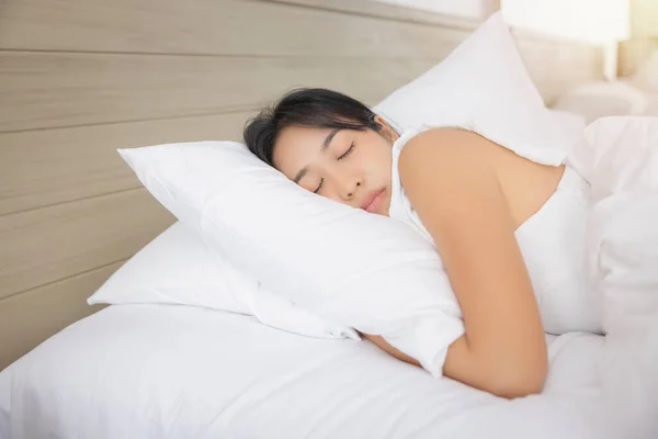 Young asian woman sleeping in bed at bedroom. she is lying on side and relax with eyes closed.