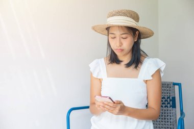Photo of young woman happy in a white dress and straw hat positive smile use smartphone. Concept of social, technology, travel, rest.